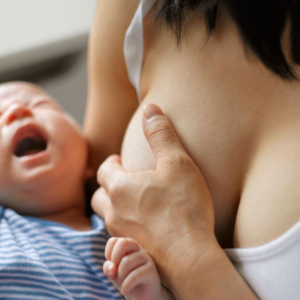 Nursing mother cradling a crying newborn, photograph